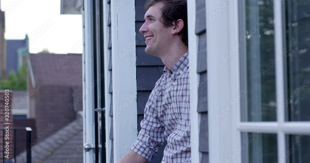 Trendy man in late 20s laughing and smiling outdoors on rooftop