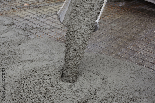 wet concrete falls from concrete bucket. Industrial construction.