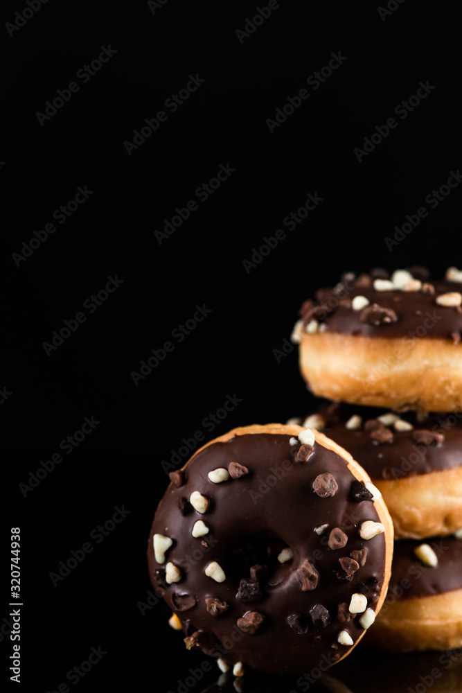 Stack of Chocolate Donuts or Doughnuts on Black Background with Copy Space Stack of Chocolate Donuts or Doughnuts on Black Background with Copy Space