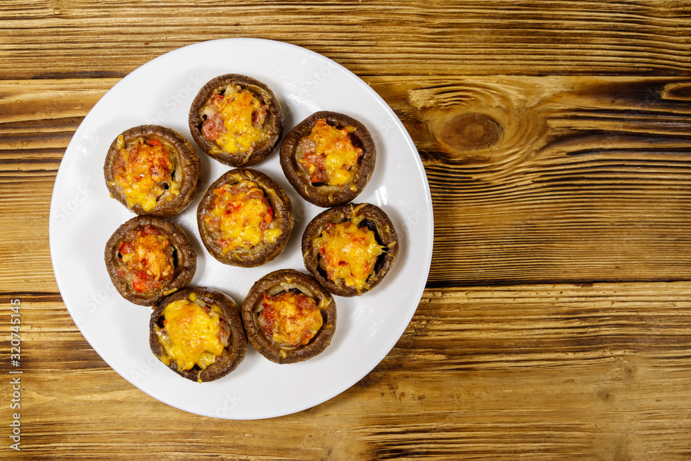 Baked mushrooms stuffed with minced meat, mushroom, paprika, onion and cheese on wooden table. Top view