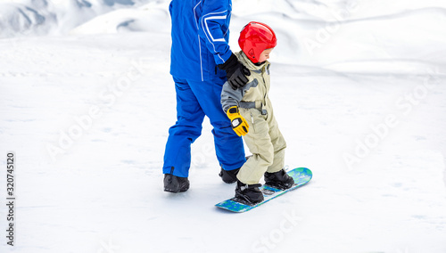 Child on the slopes for the first time on a snowboard