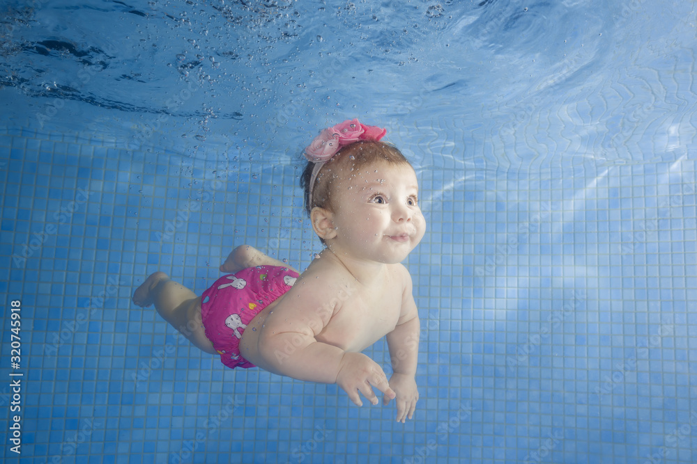 Little baby learning to swim underwater in a swimming pool