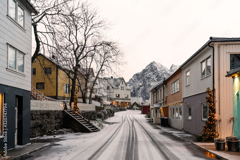Empty village street after Christmas holidays, road and houses covered with fresh snow. Henningsvaer, Lofoten islands.