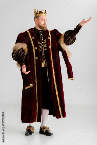 king with crown pointing with hand on grey background