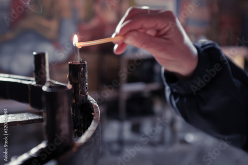 Woman's hand lighting candle at church shrine for the living