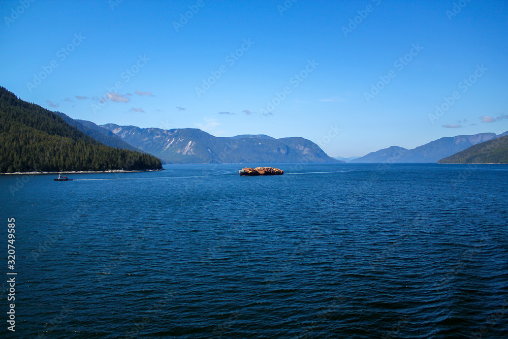 Boat transporting wood on the Inside Passage in Canada / British Columbia Boat transporting wood on the Inside Passage in Canada / British Columbia