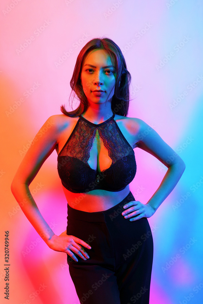 Beauty fashion portrait of female in black lingerie with colorful neon light