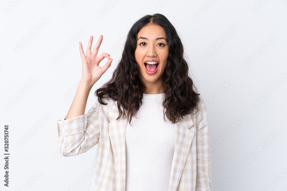 Mixed race woman over isolated white background surprised and showing ok sign Mixed race woman over isolated white background surprised and showing ok sign