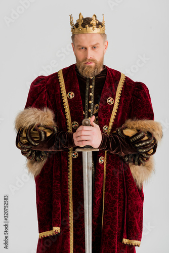 serious king with crown holding sword isolated on grey photo