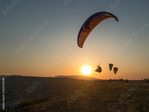 Silhouette of the group of paragliders flying at sunset.