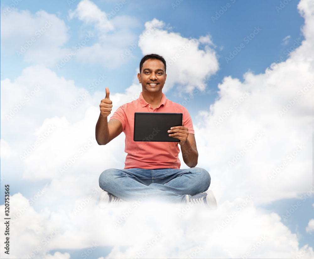 technology, internet and people concept - happy indian man with tablet computer in clouds over blue sky background