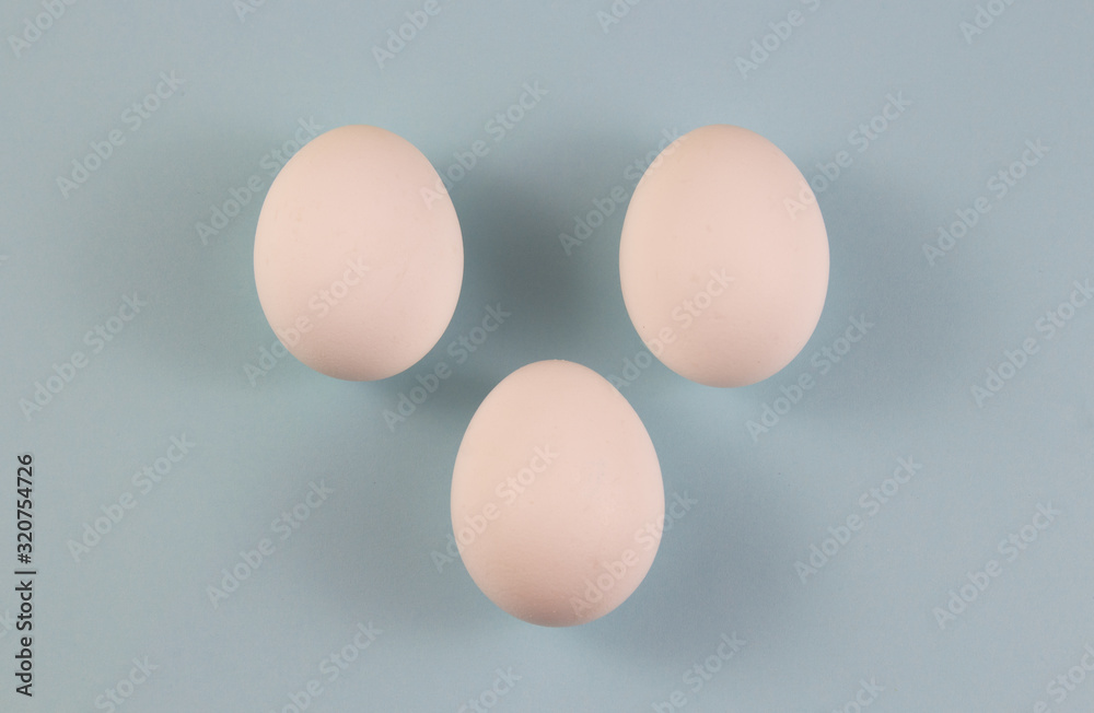 Three white chicken eggs on a blue background. place for text, easter holiday concept