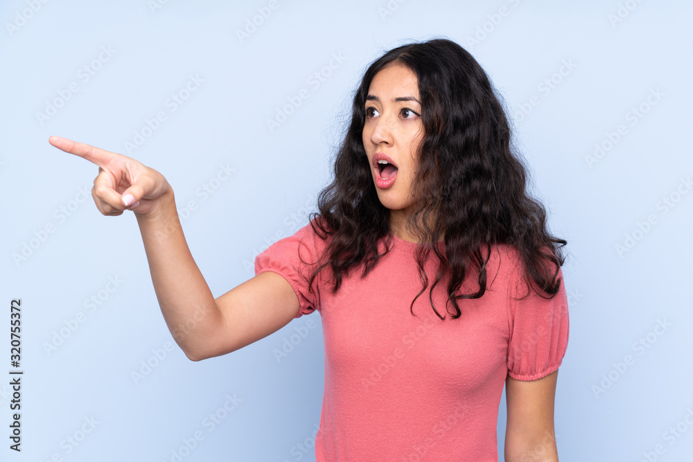 Mixed race woman wearing a sweater over isolated blue background pointing away Mixed race woman wearing a sweater over isolated blue background pointing away