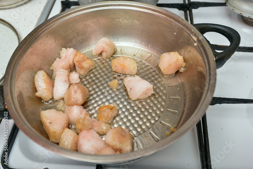 Pork fat is fried in a pan on a gas stove in the kitchen at home.
