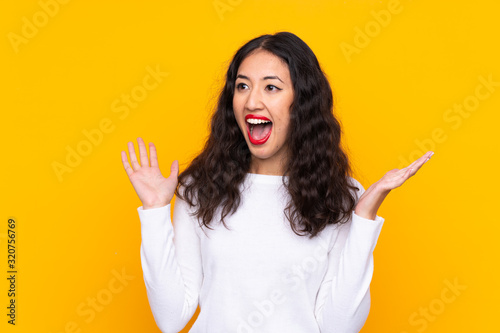 Mixed race woman over isolated yellow background with surprise facial expression