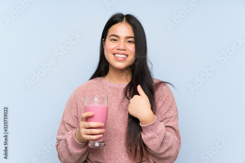 Young teenager Asian girl with strawberry milkshake with surprise facial expression