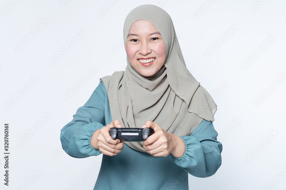 Asian Muslim woman playing console with wireless controller.