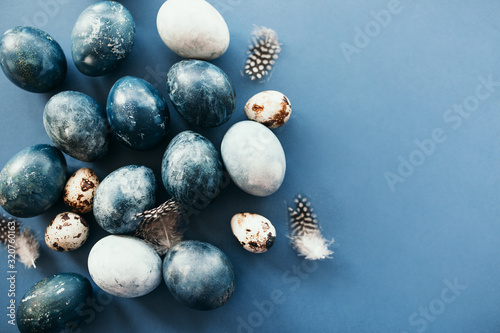 Beautiful group ombre blue Easter eggs with quail eggs and feathers on a blue background. Easter concept. Border eggs. Copy space for text