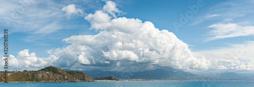 Panoramic view of the Milazzo coast with large white clouds above. Slightly noisy photography. Milazzo, Sicily, Italy