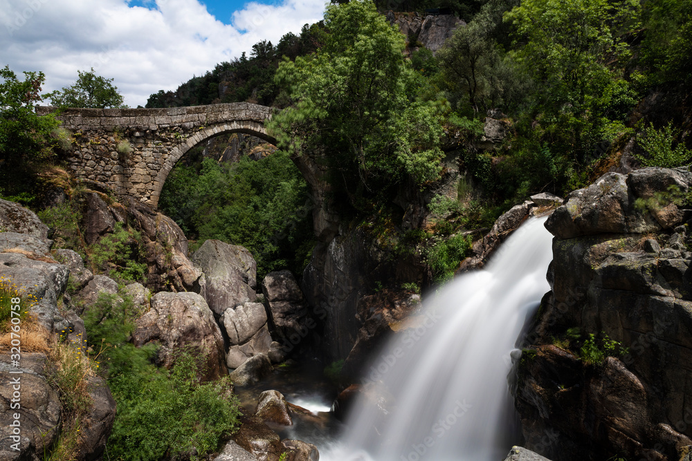View of the ancient Mizarela Bridge (or Devil’s Bridge) with a waterfall, at the Peneda Geres National Park, in Portugal, Europe View of the ancient Mizarela Bridge (or Devil’s Bridge) with a waterfall, at the Peneda Geres National Park, in Portugal, Europe
