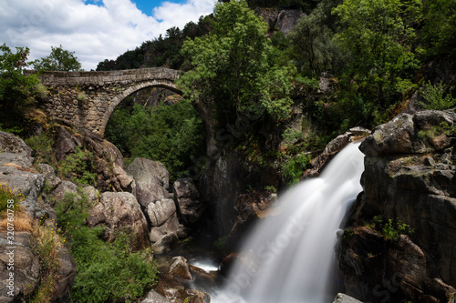 View of the ancient Mizarela Bridge (or Devil’s Bridge) with a waterfall, at the Peneda Geres National Park, in Portugal, Europe