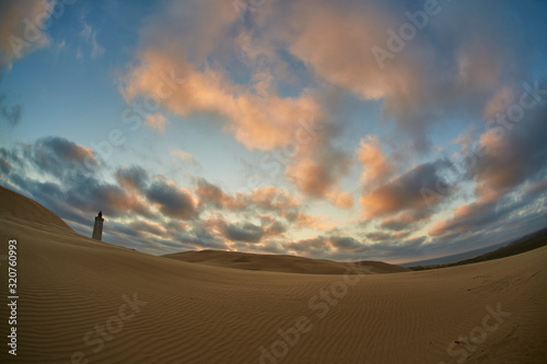 Lighthouse on beach in sunset photo