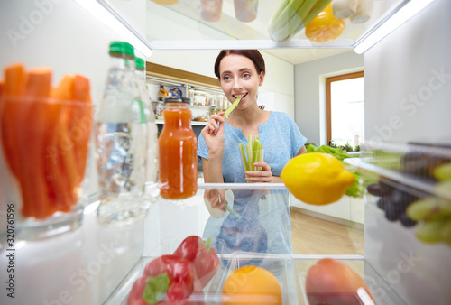 Young woman taking fresh healthy vegetables from the fridge and preparing lunch, diet and lifestyle concept