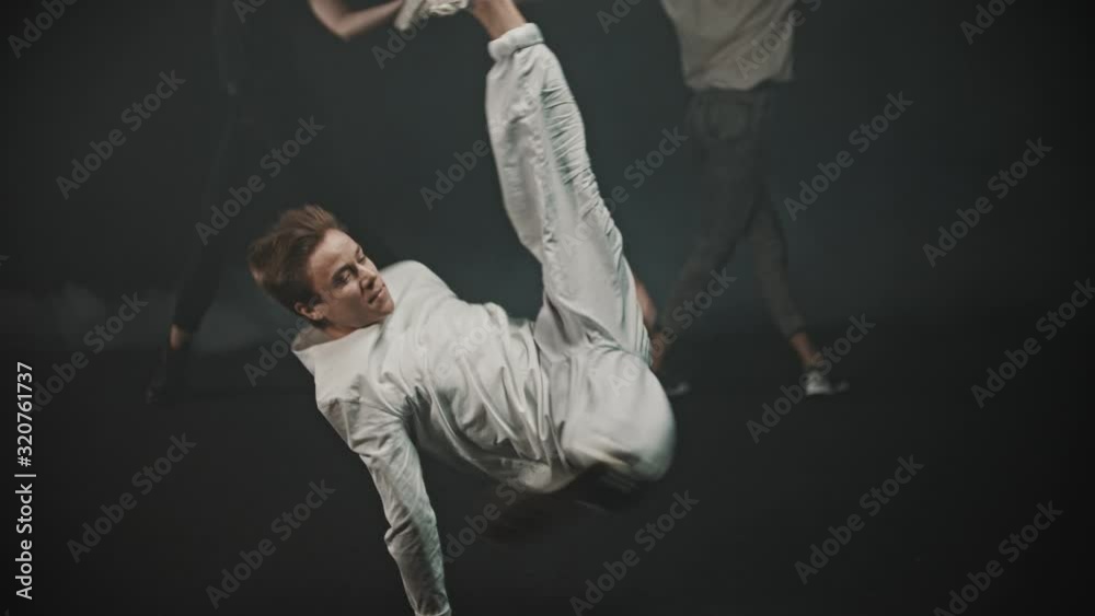 A man performing breakdancing tricks - two women dancing on the background