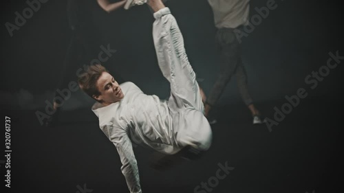 A man performing breakdancing tricks - two women dancing on the background photo