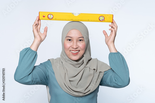 Female muslim holding a water-level tool. photo