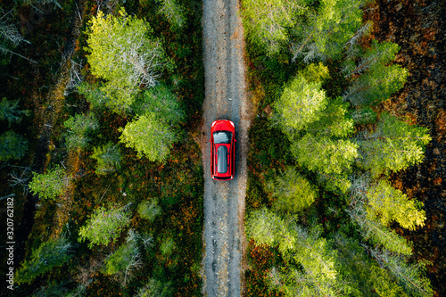 Aerial view of red car with a roof rack on a country road in Finland