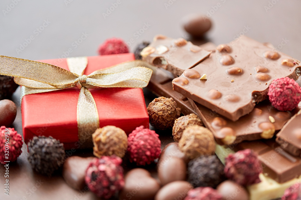 sweets, confectionery and food concept - close up of different chocolate bars, candies and gift box on brown background sweets, confectionery and food concept - close up of different chocolate bars, candies and gift box on brown background
