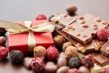 sweets, confectionery and food concept - close up of different chocolate bars, candies and gift box on brown background