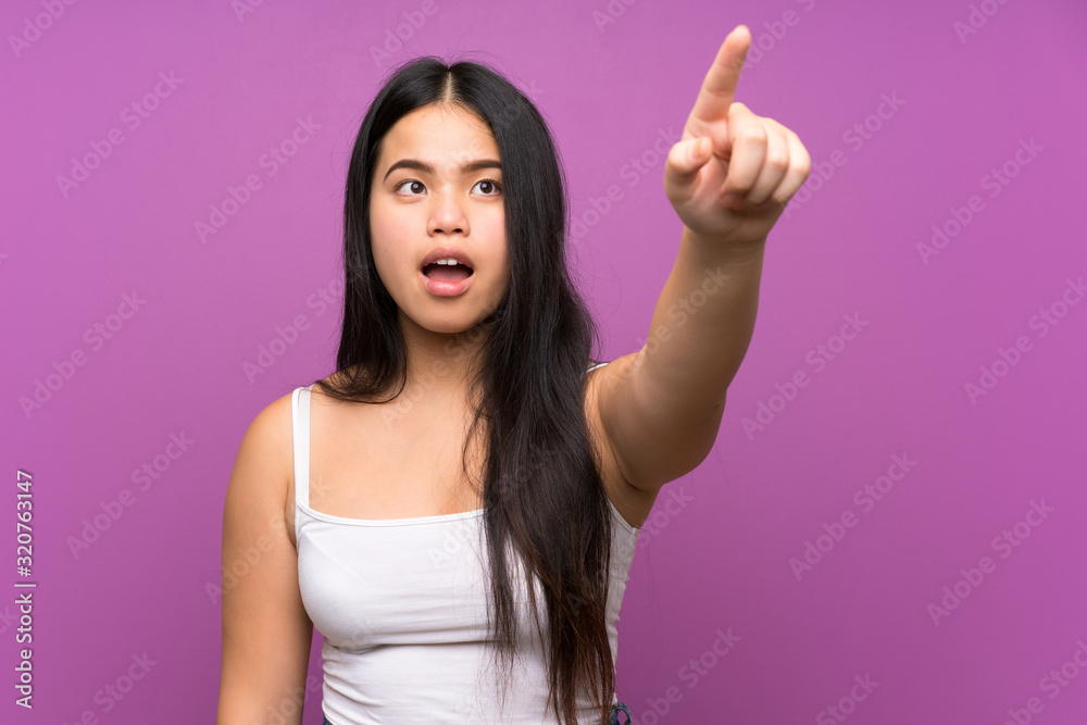 Young teenager Asian girl over isolated purple background pointing away Young teenager Asian girl over isolated purple background pointing away