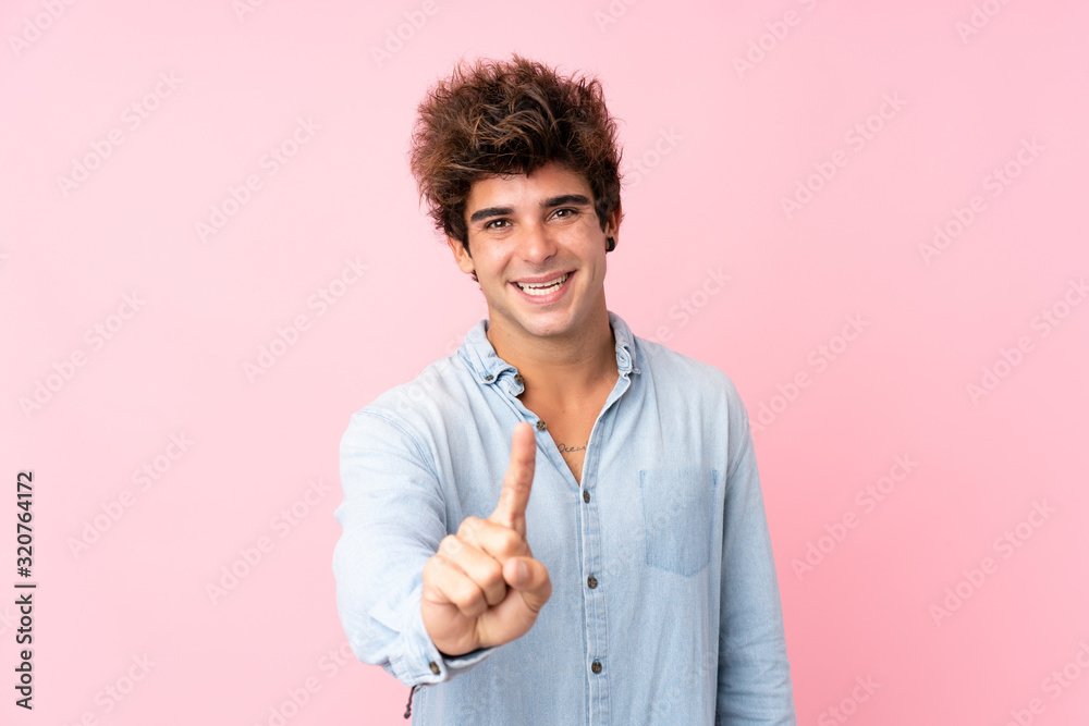 Young caucasian man with jean shirt over isolated pink background showing and lifting a finger Young caucasian man with jean shirt over isolated pink background showing and lifting a finger