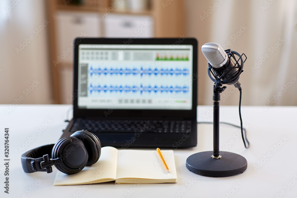 post production and technology concept - microphone, laptop computer with sound editor program, headphones and notebook on table at home office - obrazy, fototapety, plakaty 