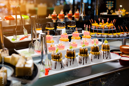 Delicious reception candy bar dessert table. Pieces of sweets cake dessert on a plate.