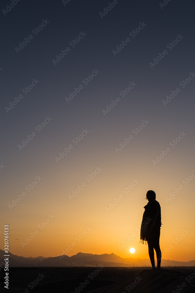 women sihouette with long scarf during sunset in desert in Yazd, Iran