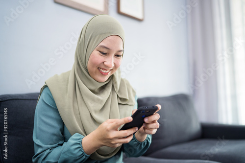 Beautiful muslim woman using her mobile device with facial expression.