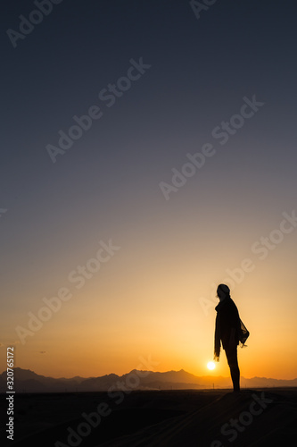 women sihouette with long scarf during sunset in desert in Yazd, Iran