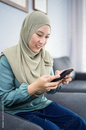 Beautiful muslim woman using her mobile device with facial expression.