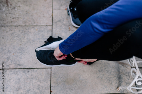 Young sportswoman tying her shoelaces before the training