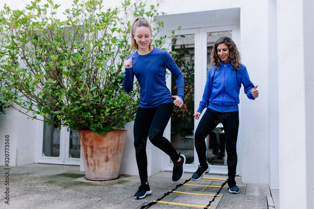 Obraz premium Two young women doing agility ladder exercise on a terrace