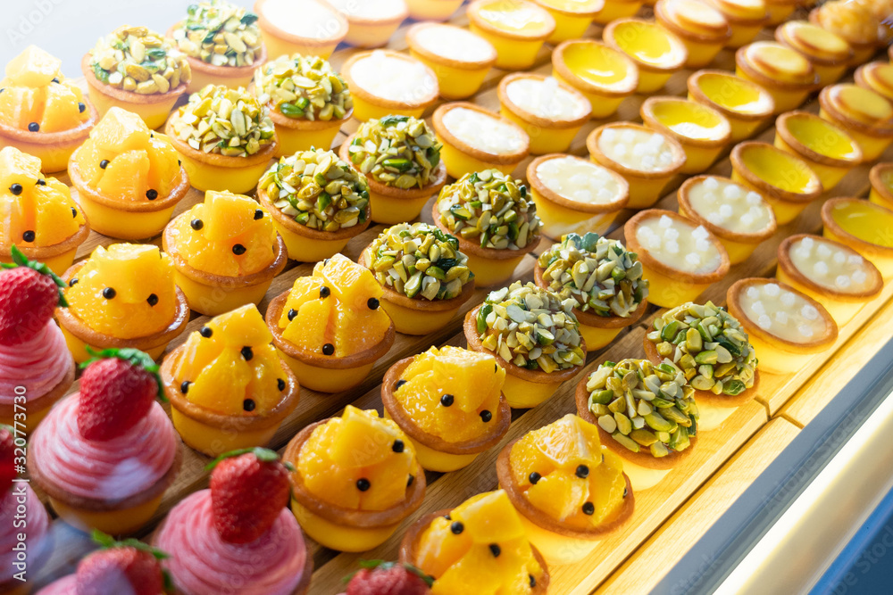 Obraz premium Various flavors of fruit mini pie desserts being displayed inside a transparent glass cabinet