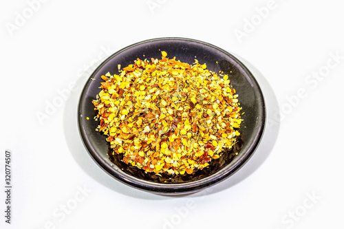 Hot seasoning in plate isolated on white background. Mix of different spices and sea salt. Traditional ingredient for cooking Italian food