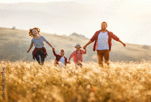 Happy family: mother, father, children son and daughter runing and jumping on sunset.
