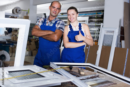 Smiling workers posing in assembly shop of windows