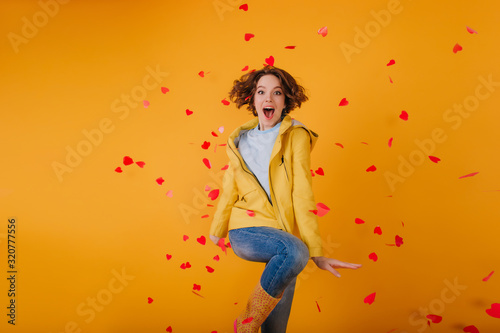 Well-dressed girl dancing, surrounded by red hearts. Indoor photo of gorgeous brunette female model celebrating valentine's day.