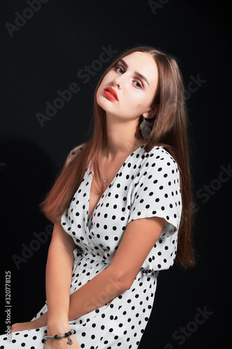 Portrait of a young attractive girl with long hair and red lips against black background.