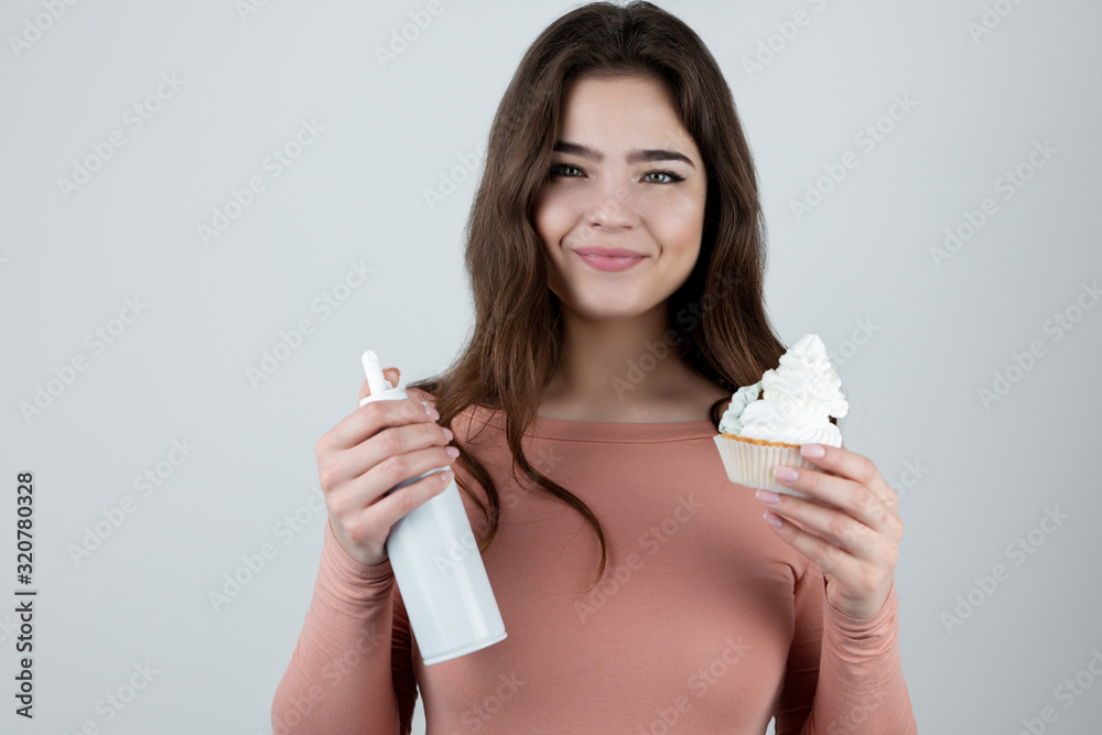 Εκτύπωση καμβά young woman holding whipped cream in one hand and cup cake in another looking sa